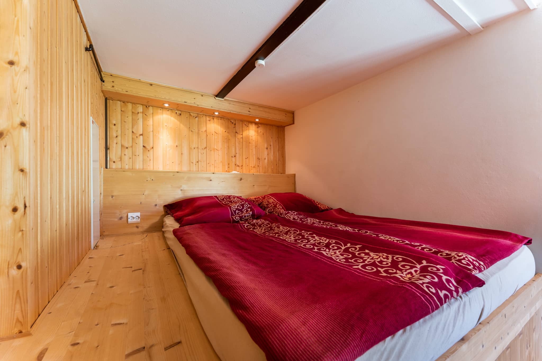 Holzvertäfeltes Schlafzimmer mit rotem dekorativem Bettbezug